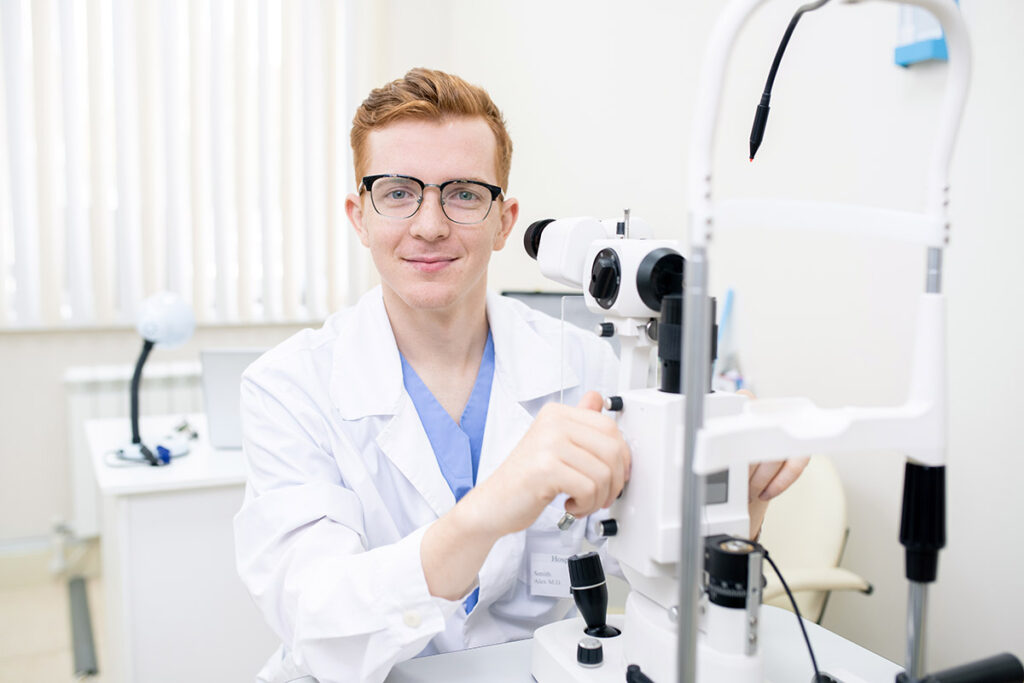 Óptico joven operando lámpara de hendidura durante examen visual en Óptica Giner.