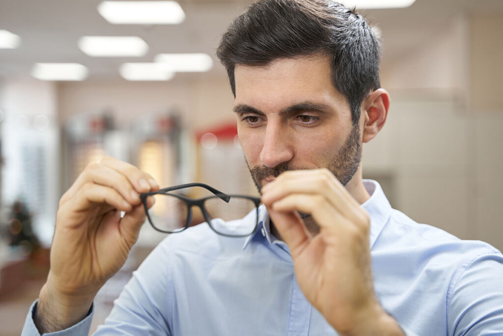 Hombre probándose unas gafas en tienda especializada, selección de monturas en Óptica Giner.