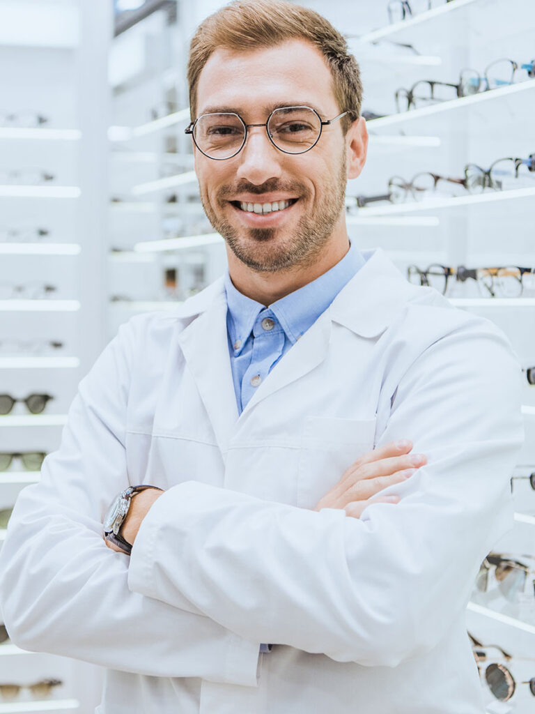 Óptico joven con gafas y bata blanca posando en la tienda de Óptica Giner.